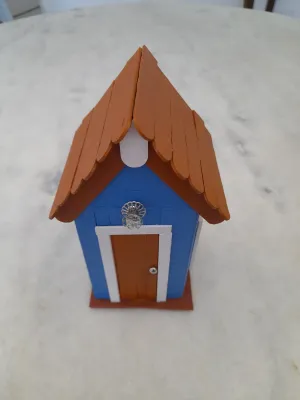 Mini casa decorado com palito no interior tem luminária nas cores azul , branco e marrom